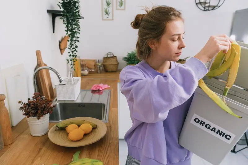 A woman composts banana peels in an indoor organic bin, promoting sustainable living