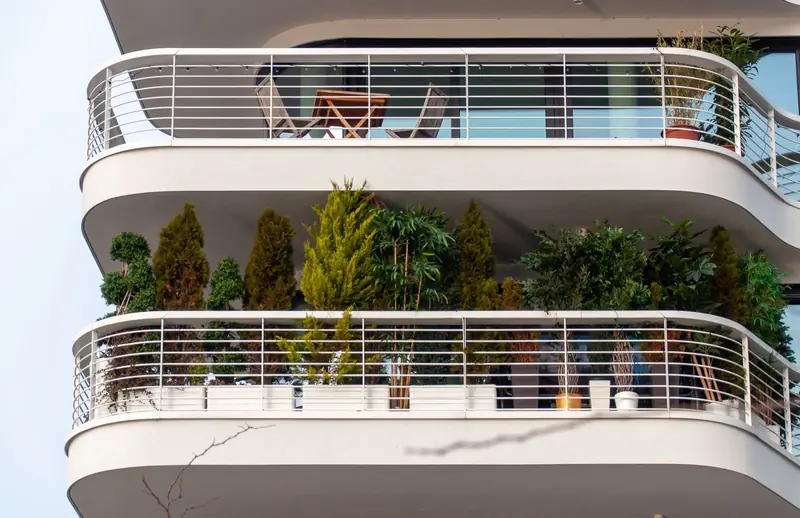 Sophisticated apartment balcony adorned with lush plants and stylish furniture, showcasing modern living