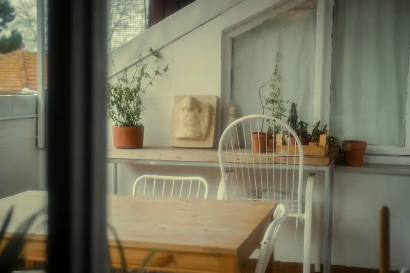 A serene indoor balcony with chairs, potted plants, and soft lighting decor